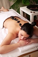 Woman in wellness and spa setting having a hot stone therapy session