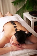 Woman in wellness and spa setting having a hot stone therapy session