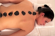 Woman in wellness and spa setting having a hot stone therapy session