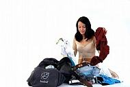 Young girl packs her bags for traveling. White background