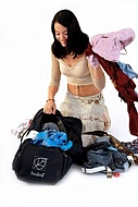 Young girl packs her bags for traveling. White background