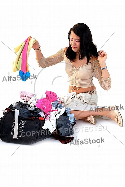 Young girl packs her bags for traveling. White background