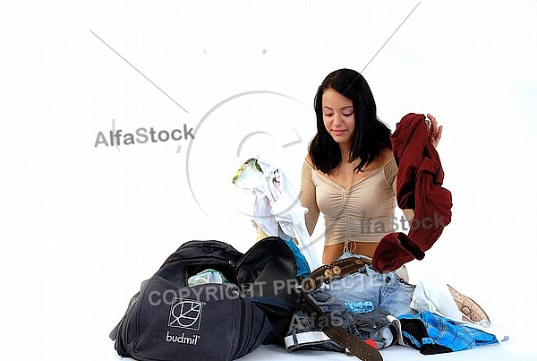 Young girl packs her bags for traveling. White background