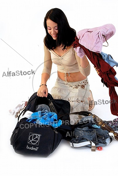 Young girl packs her bags for traveling. White background