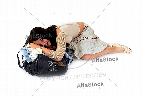 Young girl packs her bags for traveling. White background