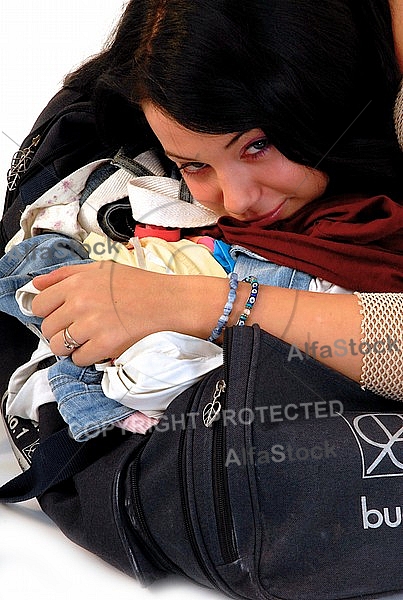 Young girl packs her bags for traveling. White background