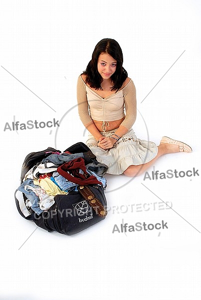 Young girl packs her bags for traveling. White background