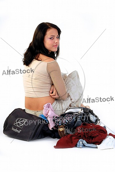 Young girl packs her bags for traveling. White background