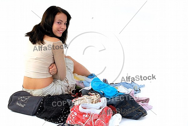 Young girl packs her bags for traveling. White background