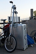 Bike with one wheel and a silver suitcase