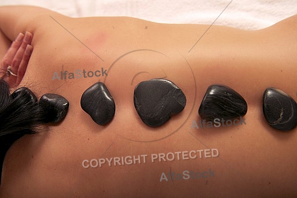 Woman in wellness and spa setting having a hot stone therapy session